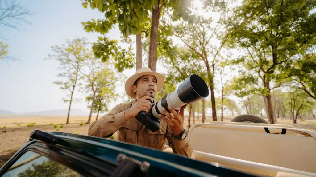A photographer holding a camera in the wild.