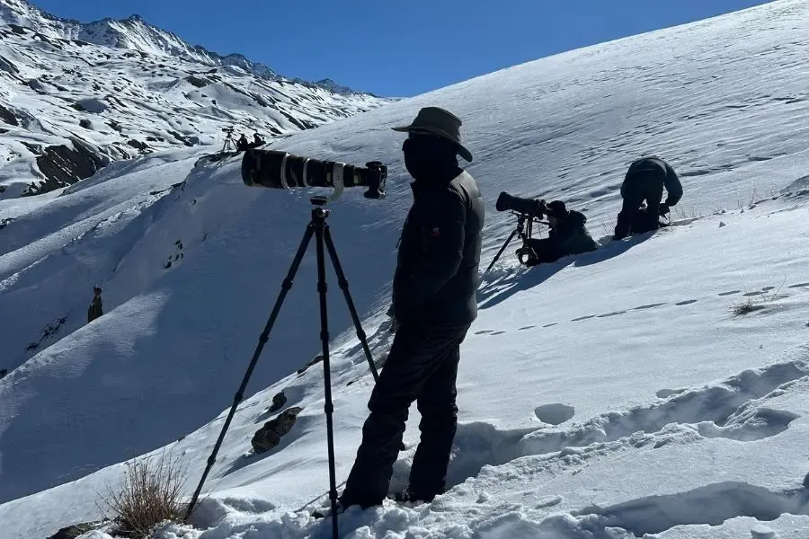 guy with a camera trying to spot a snow leopard
