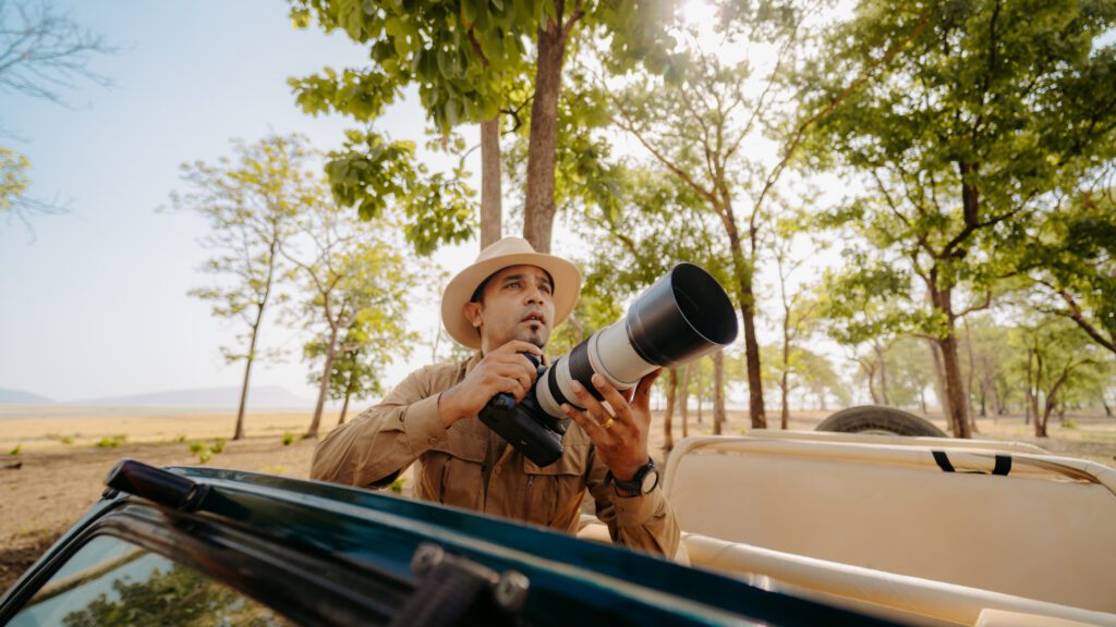 A photographer holding a camera in the wild.