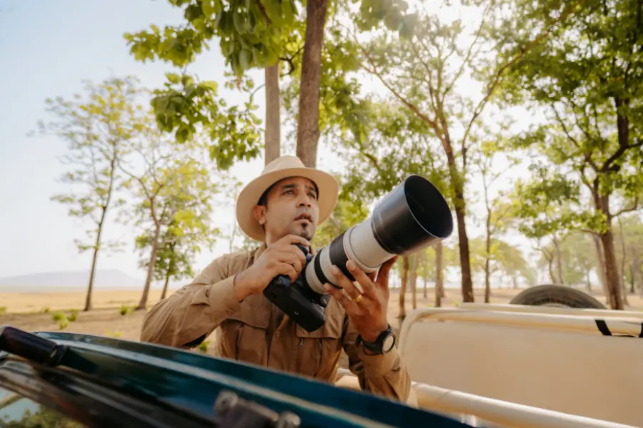 Wildlife guide holding a camera with a long lens during safari.