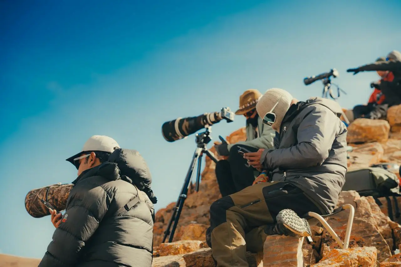 A group of expeditioners clicking pics of a Snow Leopard.