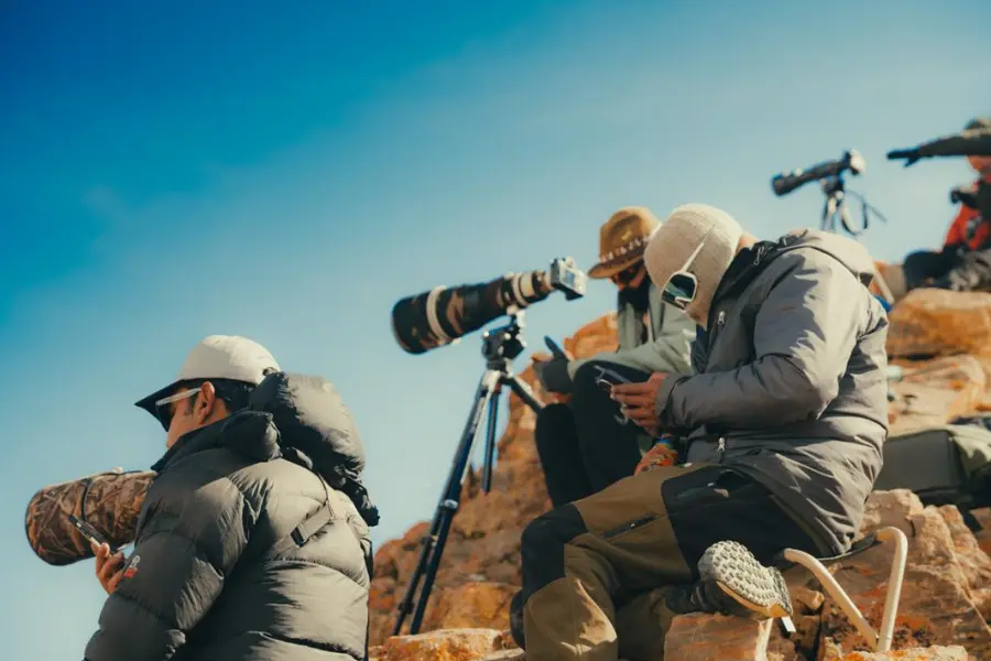 Guests with spotting scopes observing from a mountain ridge.